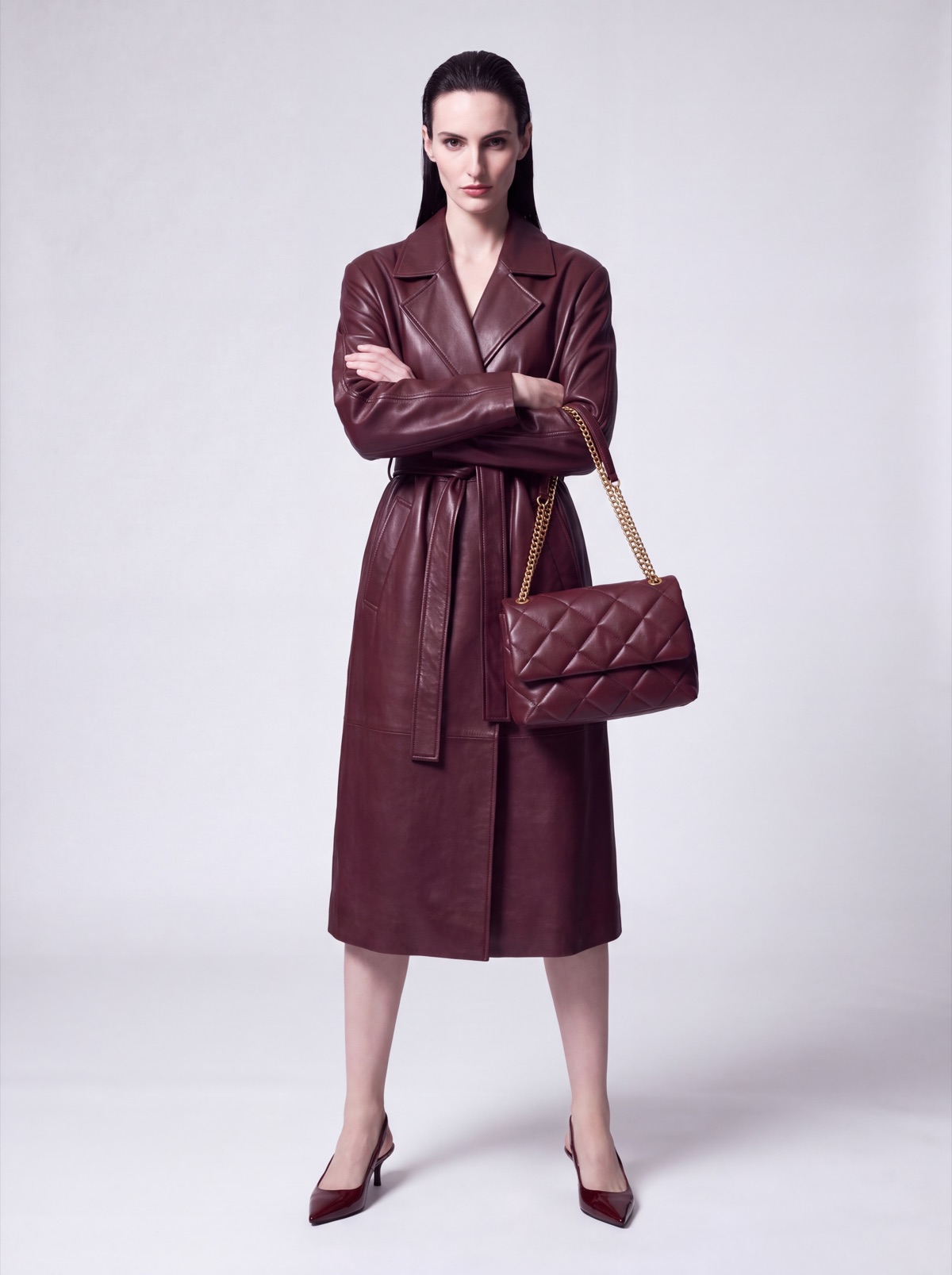 Burgundy leather trench coat on the same AI model, front view with arms crossed